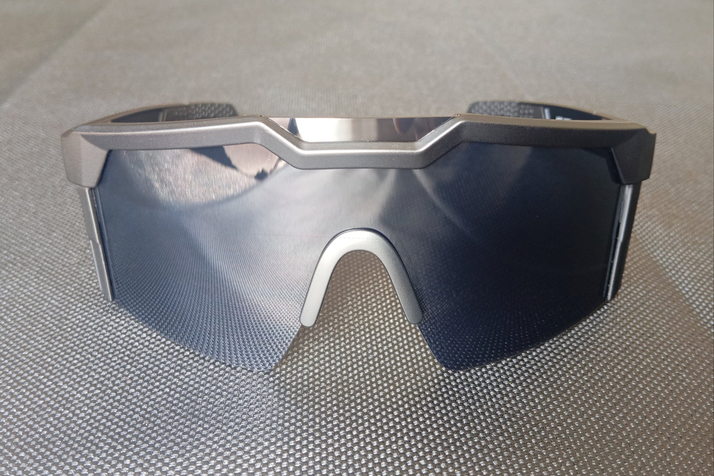 Dark sunglasses seen from the front. Comfortable black nose-pad visible. Polycarbonate lens is tinted black.