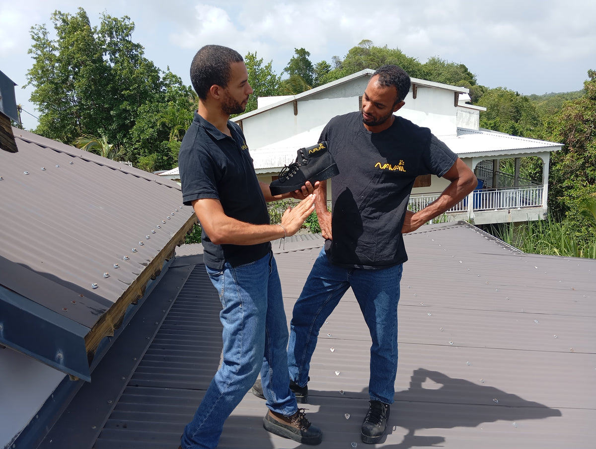 Navail brothers on a steel roof discussing with a magnetic boot in hands. They are both wearing magnetic boots.